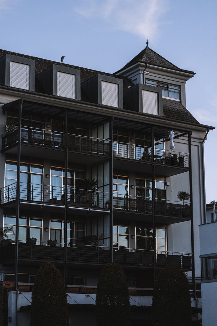 A modern residential building featuring balconies and a dark facade in an outdoor urban setting.